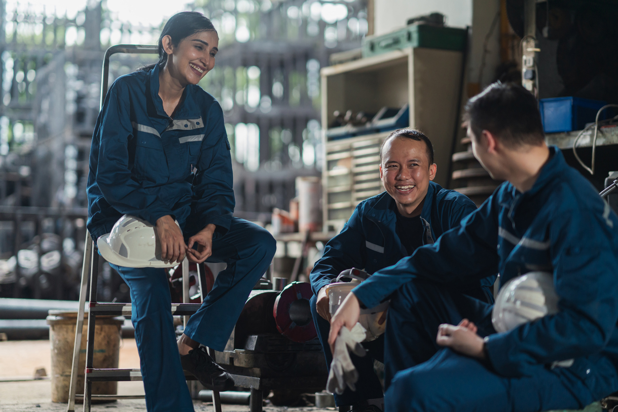 A group of diverse Asian factory workers having a hearty conversation while taking a break