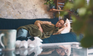 Shot of a young woman experiencing stomach pain while lying on the sofa at home