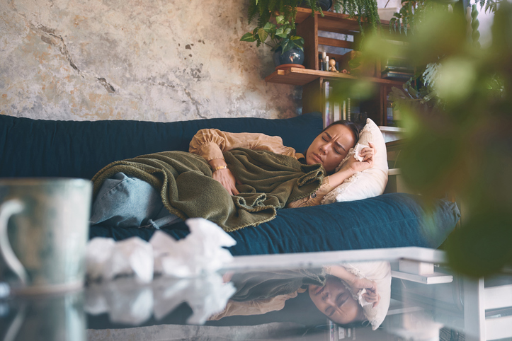 Shot of a young woman experiencing stomach pain while lying on the sofa at home